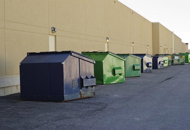 a construction worker empties a wheelbarrow of waste into the dumpster in Brentwood